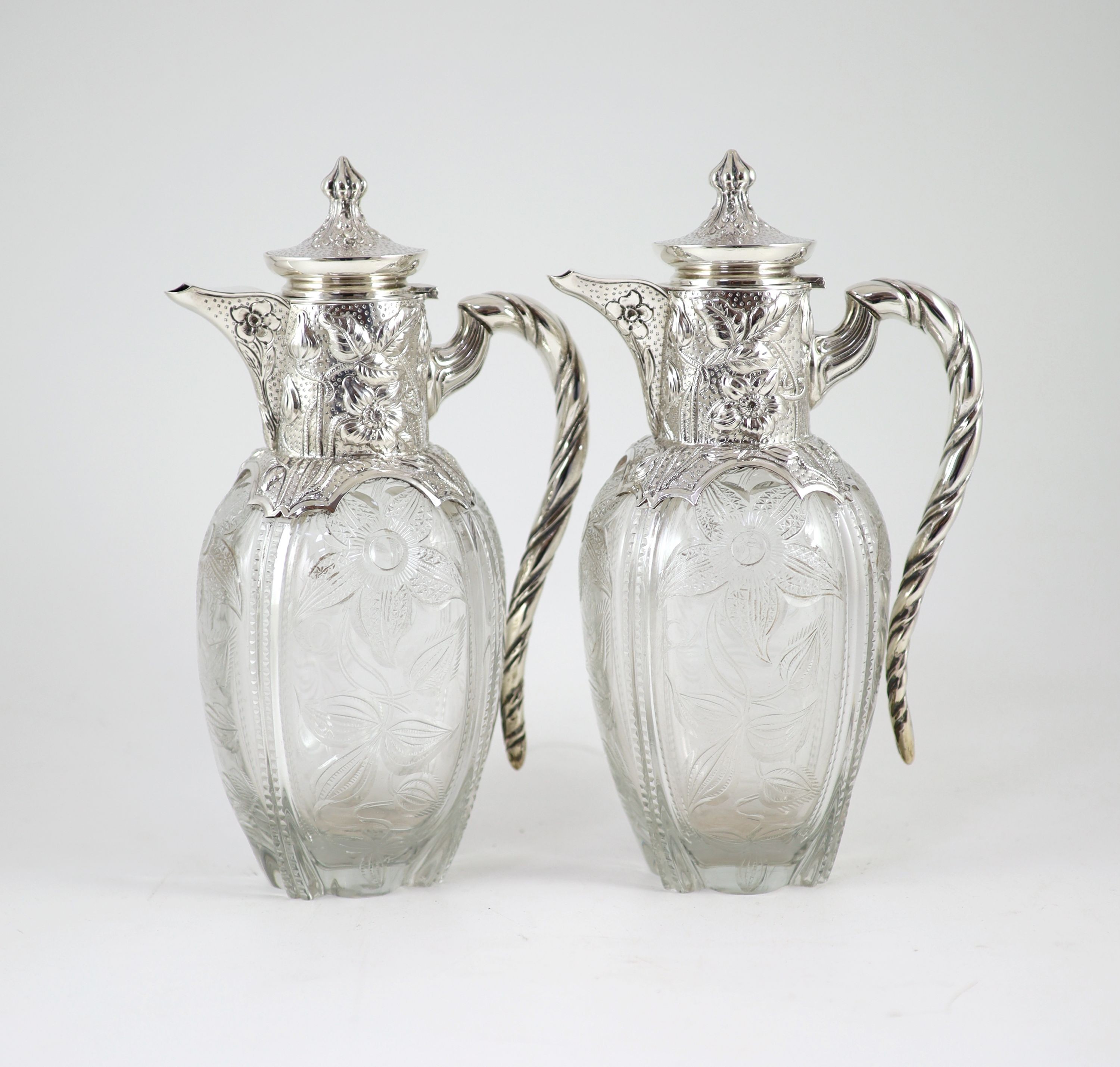 A good pair of late Victorian silver mounted ‘rock crystal’ glass claret jugs, with hinged covers, by John Grinsell & Sons